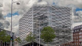 Copenhagen, Denmark - July 24, 2022: Modern gray, glass and steel Nykredit bank building at corner of Puggaardsgade and Kalvebod Brygge under blue clo