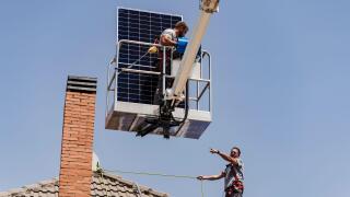 Electricians with solar panel on roof of house