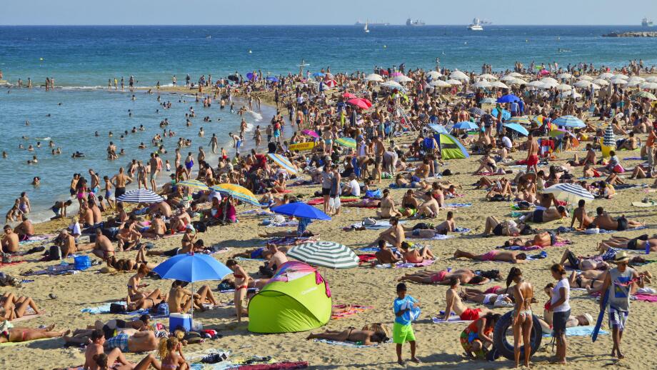 Crowded Barceloneta beach, hot summer day in Barcelona Spain.