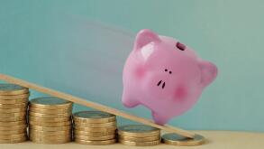 Piggy bank on decreasing piles of coins - Concept of finance and losing money