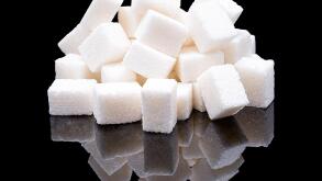 Cubes of white sugar from sugar beet with a real reflection on a black glossy background