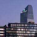 Glass building headquarters of the French bank BNP Paribas with the logo sign illuminated at sunset. Milan, Italy.