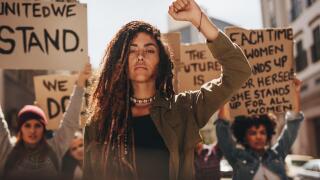 Woman leading a group of demonstrators on road. Group of female protesting for equality and women empowerment.
