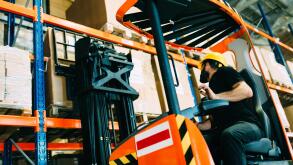 Warehouse worker doing logistics work with forklift loader