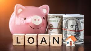 Real estate sale, savings, home loans market concept. model house with text loan on wooden cube, smilely pink Piggy bank and bank note