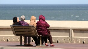 Group of women with backs to camera on very windy day seated on a bench near a sea wall.. Image shot 2009. Exact date unknown.