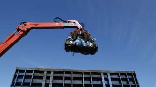 A crushed car is lifted by a crane after being crushed at a scrap yard.