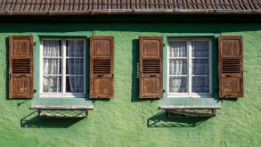 A green house with wooden shuttered windows