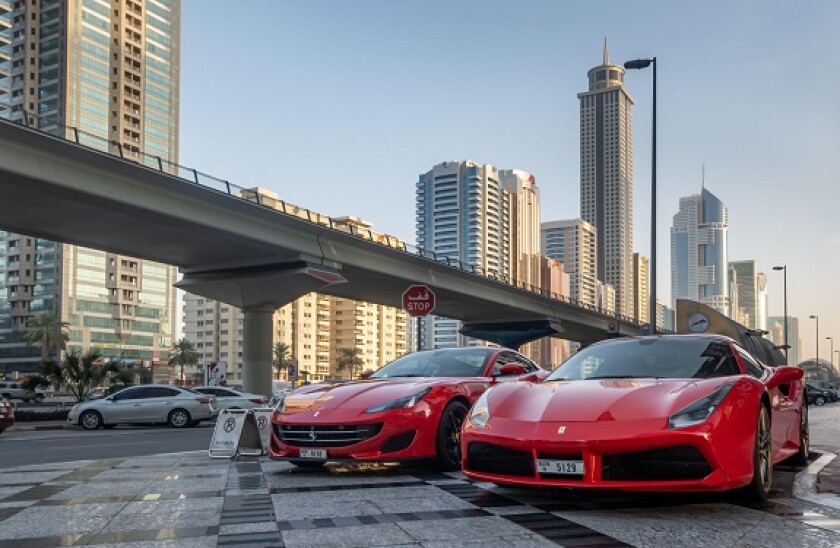 2 red Ferrari's parked near the Sheikh Zayed Road, with the metro line close by Dubai, United Arab Emirates (UAE).