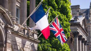 French flag and Union Jack flying side by side on flagpoles outside a historic building in Edinburgh, UK. Might depict European travel or allied natio