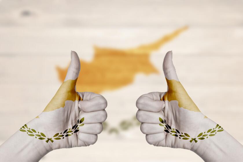 Cyprus flag painted on female hands thumbs up with blurry wooden background