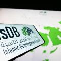 Cellphone with logo of Islamic Development Bank (IsDB) on screen in front of website. Focus on center-left of phone display.
