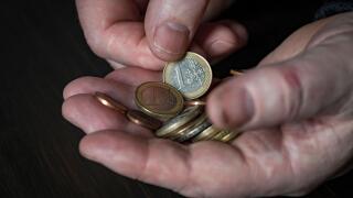 Old male hand holding euro coins, close up. Hands hold euro coins of different denominations. Inflation, purchasing power and social crisis
