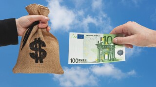 A 100 Euro bill is held in the hand. At the other side a money bag with a U.S. Dollar currency sign is held in the hand.