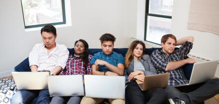 Tired business people using laptop while reclining on sofa in office